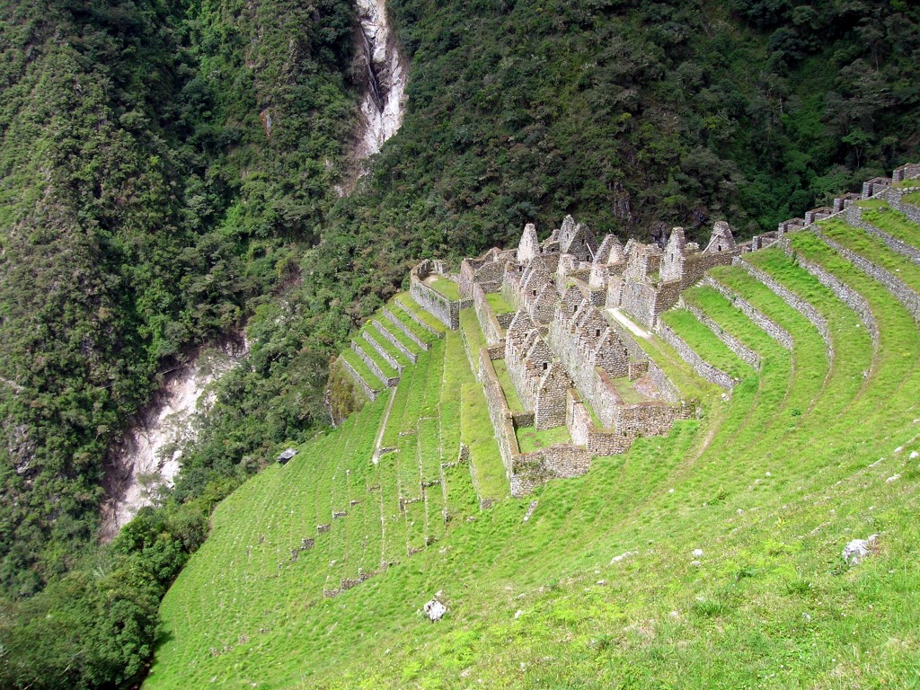 Best Hikes In Peru Image: The hillside has the remnants of old stone buildings; they form peaks but are missing roofs.