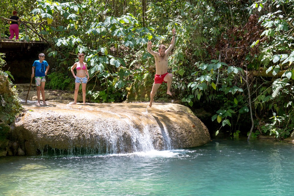 Swimming Holes Image: A group of travellers stands at a swimming hole; one is poised to jump in.