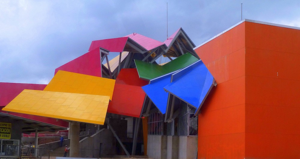 Architecture In Panama Image: An angle of Panama's Frank Gehry designed building shows yellow, magenta, pink, blue, red, and green surfaces at different angles and compositions.