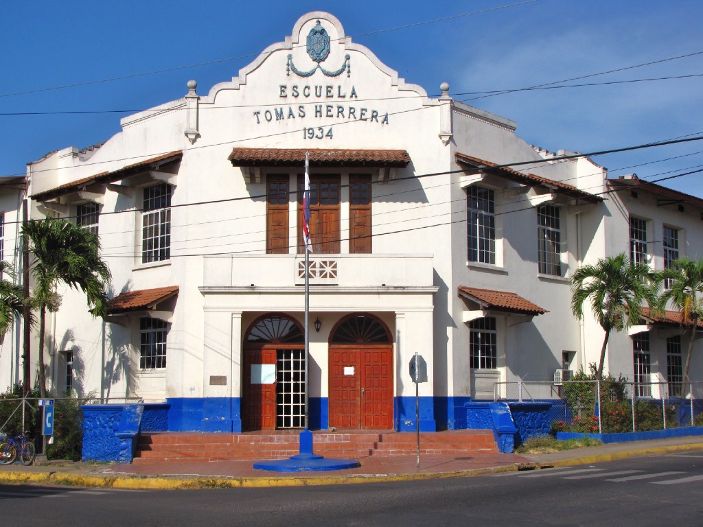 Architecture In Panama Image: Escuela Tomas Herrera is a Spanish Colonial building with red doors, and blue accents near the base of the building