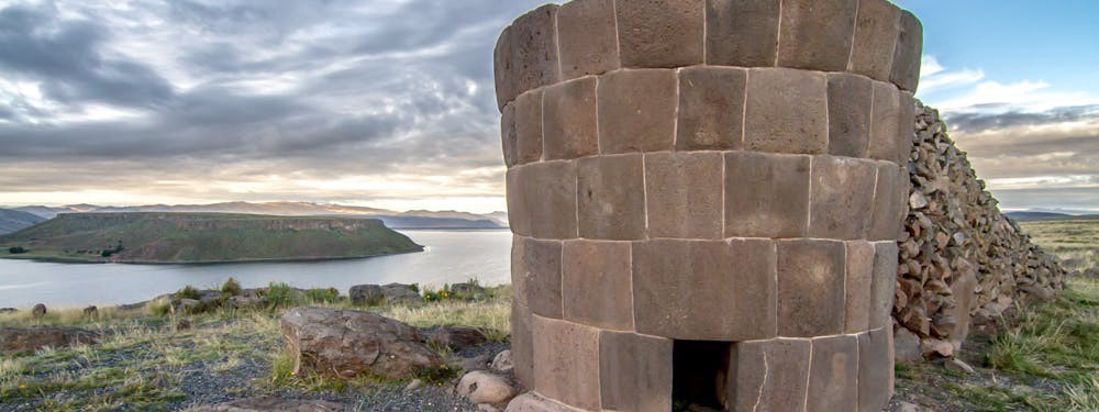 Best Hikes In Peru Image: Photograph of a funerary tower with an opening; this particular tower is overlooking the water.