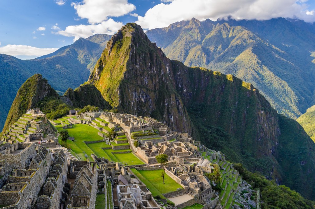 Central and South American Ruins Image: A beautiful view of Machu Picchu reveals this Central and South American ruin to be a vision of green and brown mountains, a grey aged village, and a blue sky dappled with white clouds.