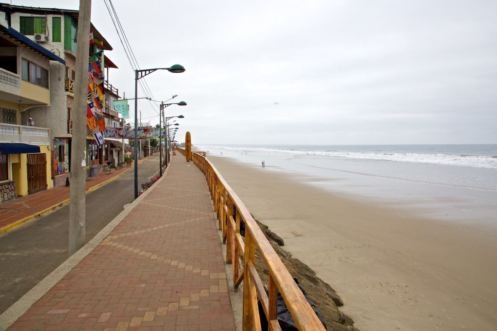 Best Surfing Beaches: Photograph of the city being divided from the nearby beach with a wooden railing and large stones.