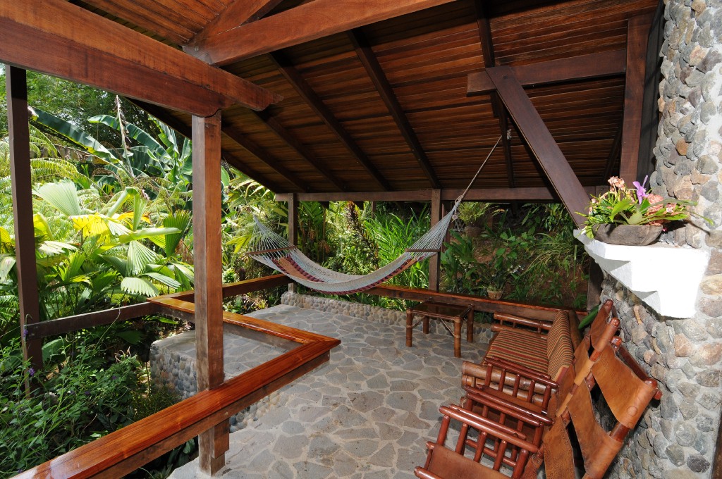 Eco-Friendly Costa Rica Image: A stony veranda has chairs, and a hammock in the corner which looks like a lovely place to read a book or take a nap.