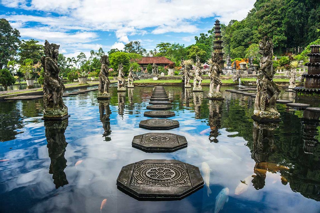 Destinations Worth Dreaming Image: A series of carved steps make a path, and is surrounded by statues. In this water feature swim koi fish. Pagodas and trees are seen along the edge.