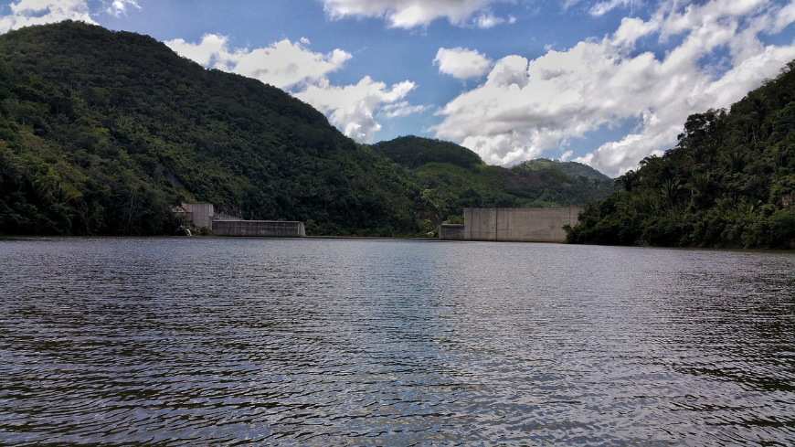 Belize River Tour Image: A dam sits in the midst of a winding river flanked by jungle. 