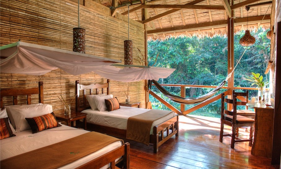 Peruvian Amazon Image: Photograph of a suite with two beds in an incredibly open thatched roof 'suite.'