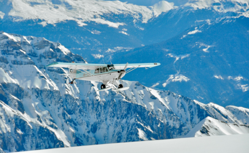 Altitude Sickness Image: A small blue and white airplane is preparing to takeoff or land on a snow covered mountain.