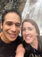 Ms. Pearson and her Mr. Lepine smile at the camera wearing black—hair wet from the waterfall in the background.