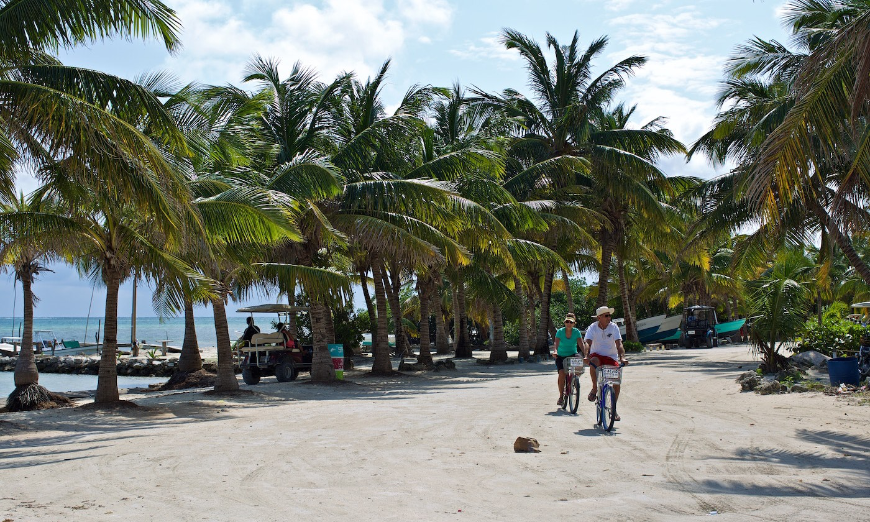 Belize Island Image: A couple cruises on bicycles near the shore of Ambergris Caye.
