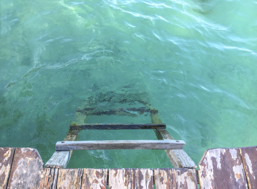 Best Beaches for Swimming in Belize Image: A ladder descends from a dock into turquoise water. 