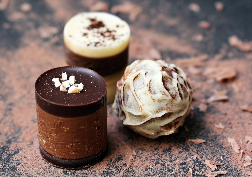 Best Chocolate Image: Three chocolate confections sit on a table dusted with cocoa powder.
