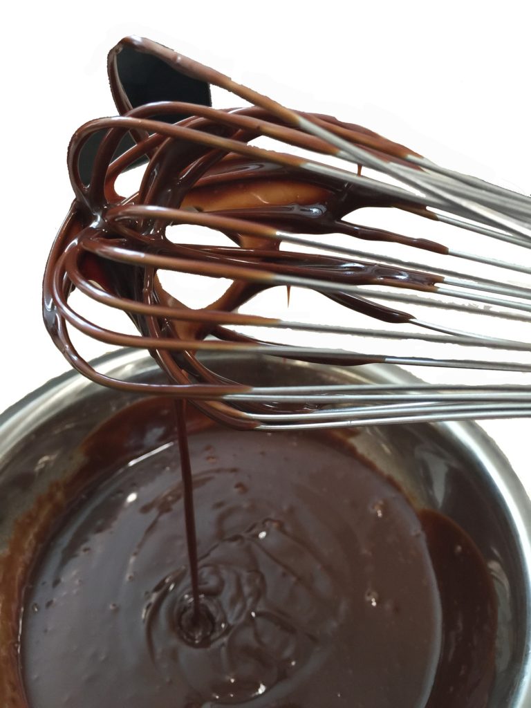 Best Chocolate Image: Chocolate ganache falls from a metal whisk into a bowl filled with ganache.