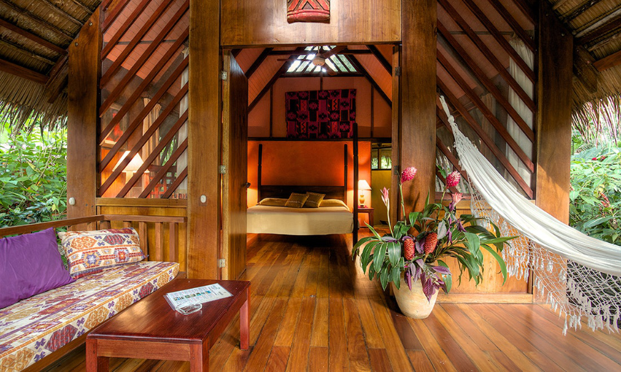 Best Ecotourism Lodges Image: A lovely rainforest suite has an en suite white hammock, large flowers, and open air thatched roof sitting area.