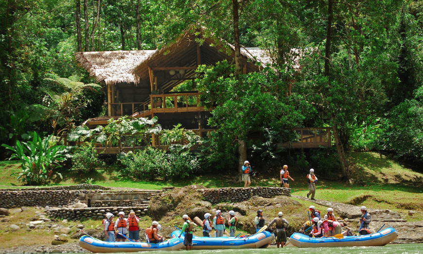 Best Ecotourism Lodges Image: A group of white water rafters sit outside of a main lodge.
