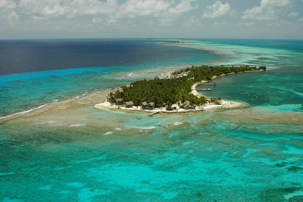 Best Surfing Beaches: An aerial view of Long Caye shows an abundance of green trees dappled with buildings along the shore.