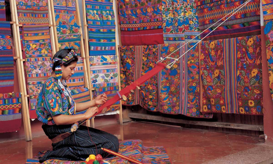 Best Travel Stories Image: A female artisan sits on the floor as she skillfully crafts handmade textiles in Guatemala.