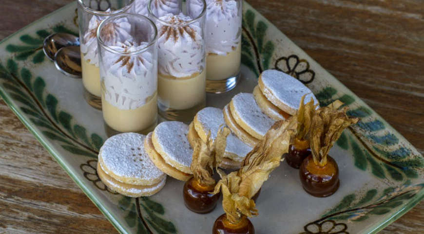 Best Travel Stories Image: A decadent tray of Peruvian desserts including a parfait in a glass, biscuits/cookies, and a treat dipped in chocolate.