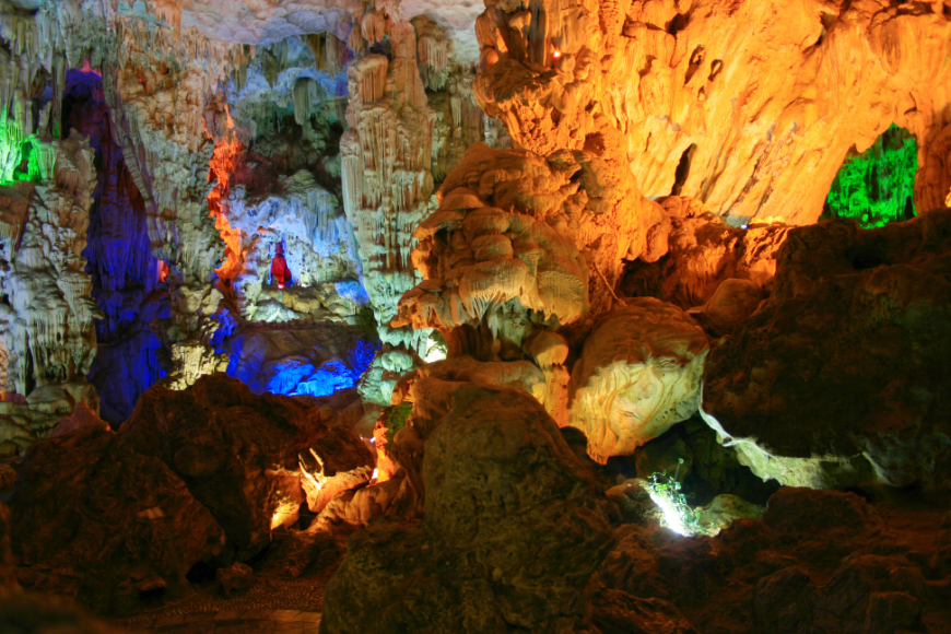 Caving in Vietnam Image: Indigo, violet, orange, and green lights illuminate sections of Thien Cung cave.