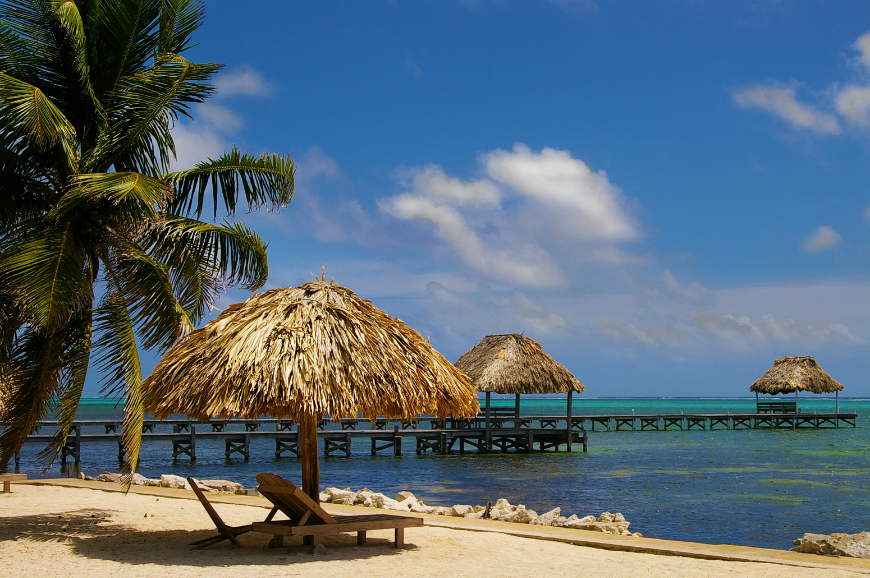 Central America in Winter Image: A lounge chair and thatched umbrella on a tropical beach.