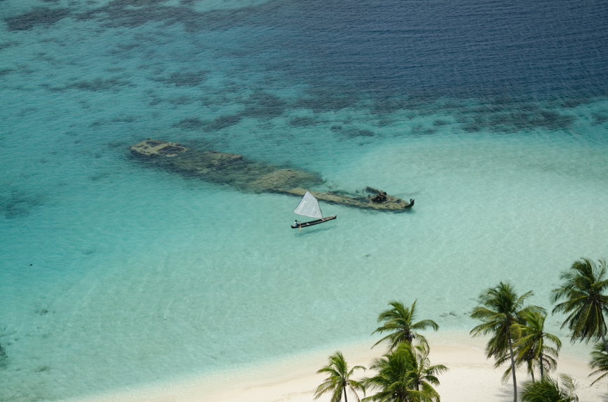 Central America Islands Image: A sailboat makes its way to a sunken shipwreck just off the coast.