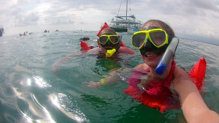 Costa Rica Mother's Day Image: The author's daughter and granddaughter take a picture in the water wearing red swimming vests, and neon yellow snorkels.