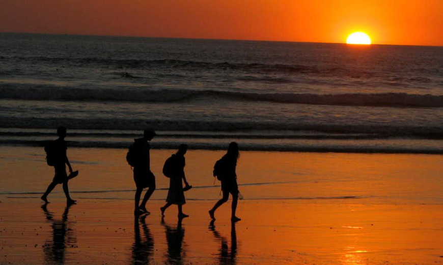 Costa Rica Villa Image: Four people walk on a beach during sunset.