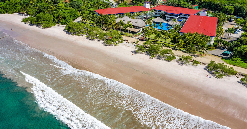Trip Postponement Image: An aerial view of red-roofed oceanside accommodations.