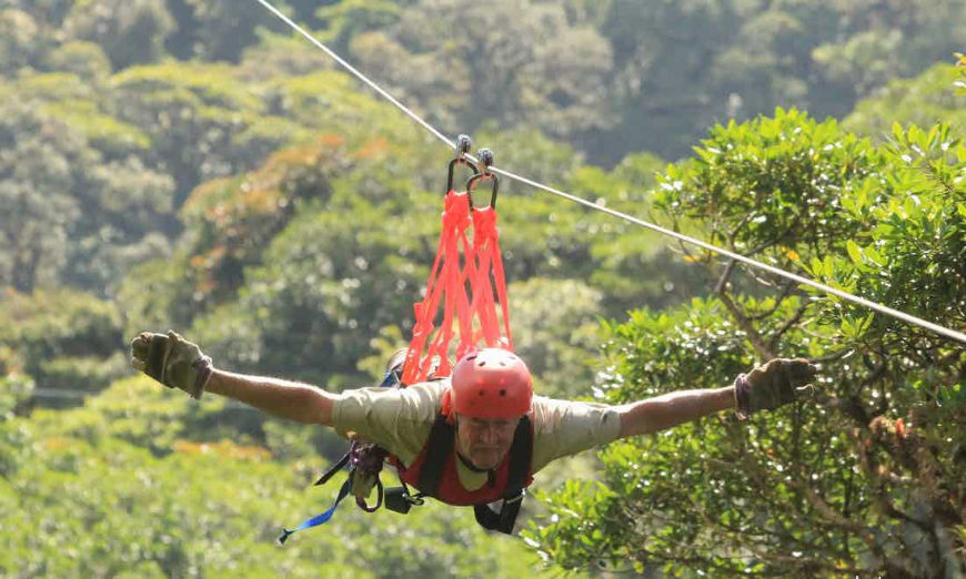 Costa Rica Rainforest Tours Image: A gentleman spreads his arms out whilst soaring over the jungle.