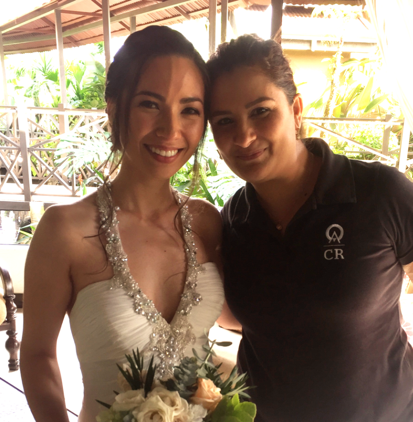 Destination Wedding Image: Left side: Features a beautiful and smiling brunette bride named Sophia; she wears her wedding gown, and holds her bouquet. Right side: Anywhere Agent Sirleny has her brunette hair pulled back, and wears a black polo.
