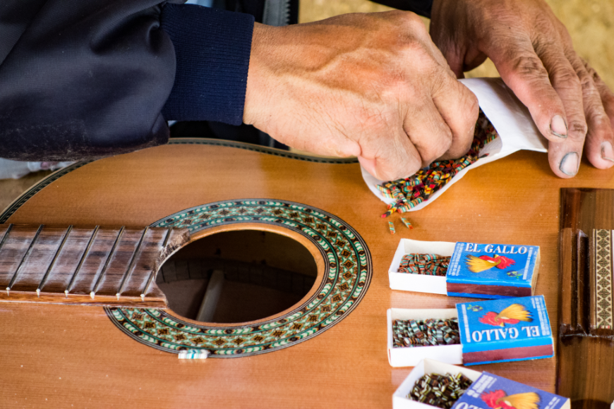 Destination Wedding in Ecuador Image: An artisan adds a colorful inlay to the guitar he is building.