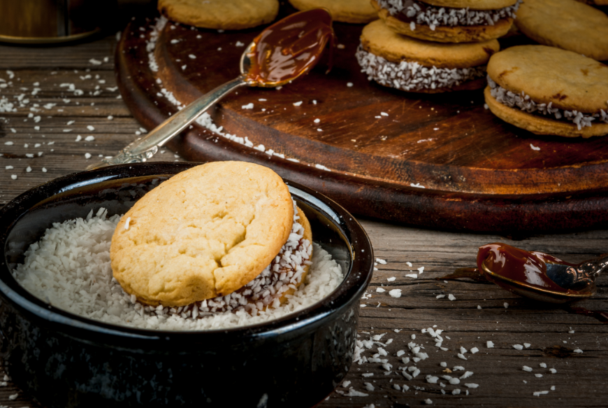 Eat In Peru Image: Alfajores, spoons in dulce de leche, and a bowl of shredded coconut.