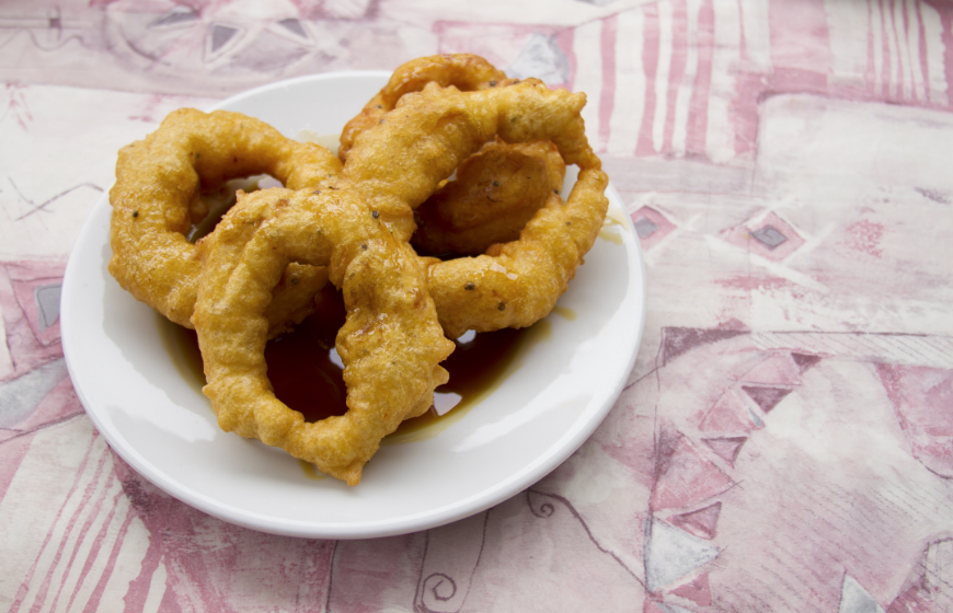 Eat In Peru Image: Picarones donuts with dipping syrup.