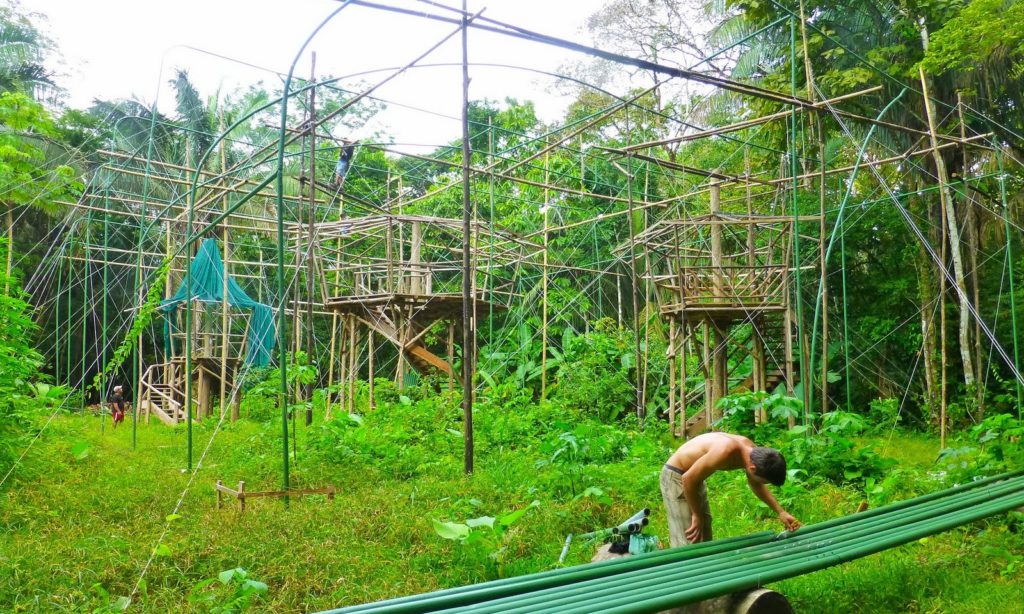 Eco-Friendly Costa Rica Image: A volunteer is working on green pipes. Behind him are the beginnings of structures made of this green pipe, and what one would assume is local wood.