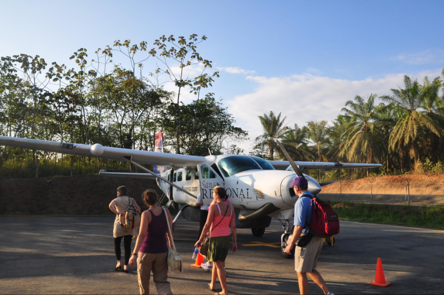 Getting Around in Costa Rica Image: Four people walk toward a small domestic airplane.