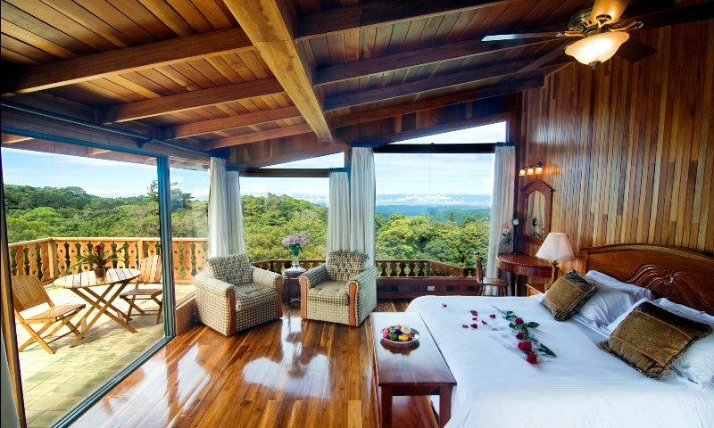 Green Season Image: A rose covered bed and balcony with bistro set and view at Belmar Hotel. 