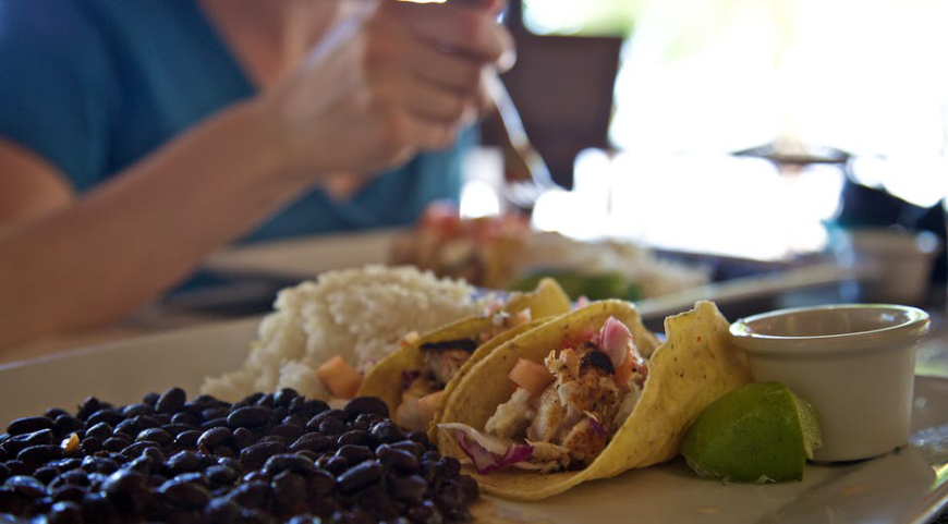 Moving to Belize Image: Close-up of a hearty helping of black beans, rice, and tacos served with a lime wedge.