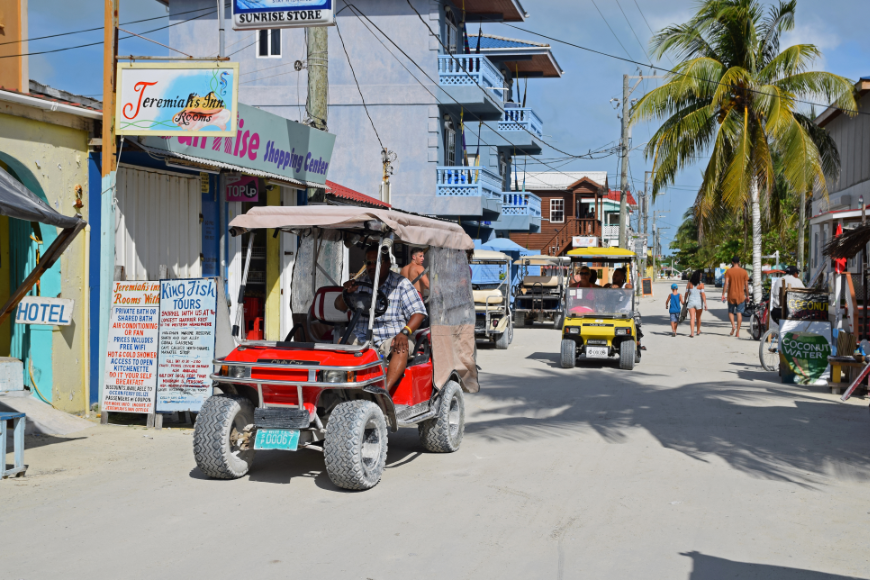 Moving to Belize Image: People walk and ride their golf carts around one of Belize's streets.