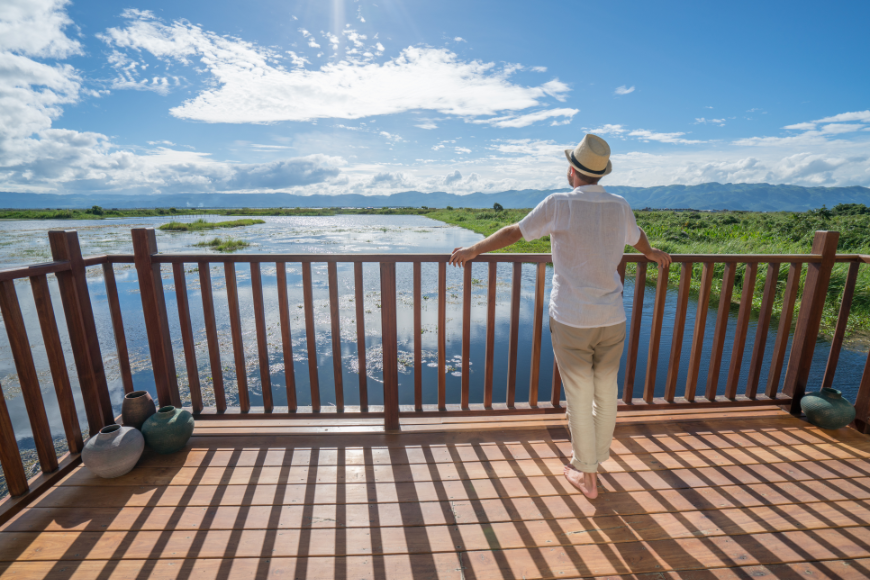 Retiring Abroad, Moving Abroad Image: A man stands on a blacony and overlooks water, sky, and land.
