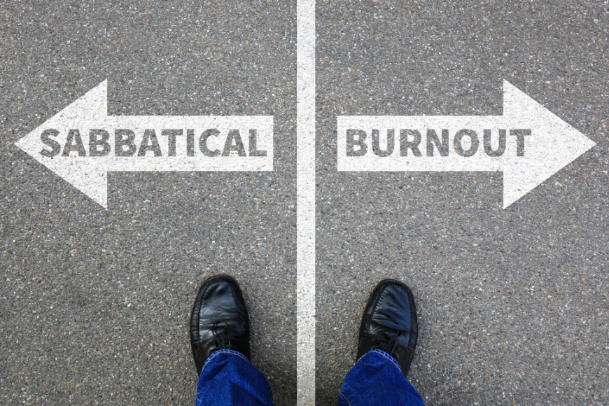 Summer In Panama Image: A white line divides white arrows with sabbatical written on the left and burnout on the right. The feet of a person wearing black shoes and blue jeans has a foot on each side.