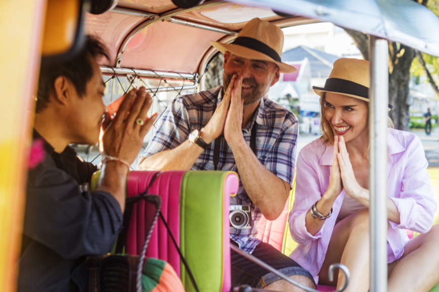 Sustainable Travel Practices Image: A tuktuk driver shows a couple a proper greeting—in this case, prayer hands. 