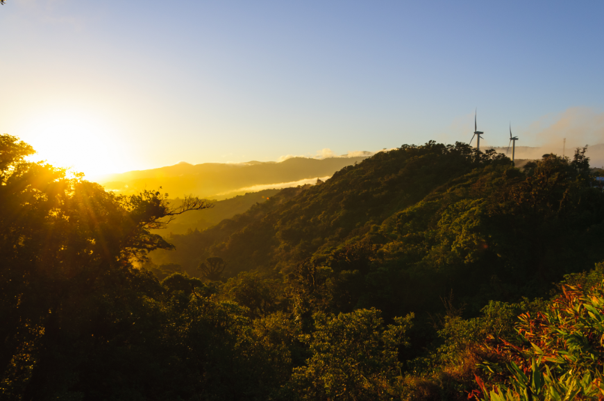 Sustainable Travel Practices Image: Sunrise over Costa Rica, with wind turbines in the background. 