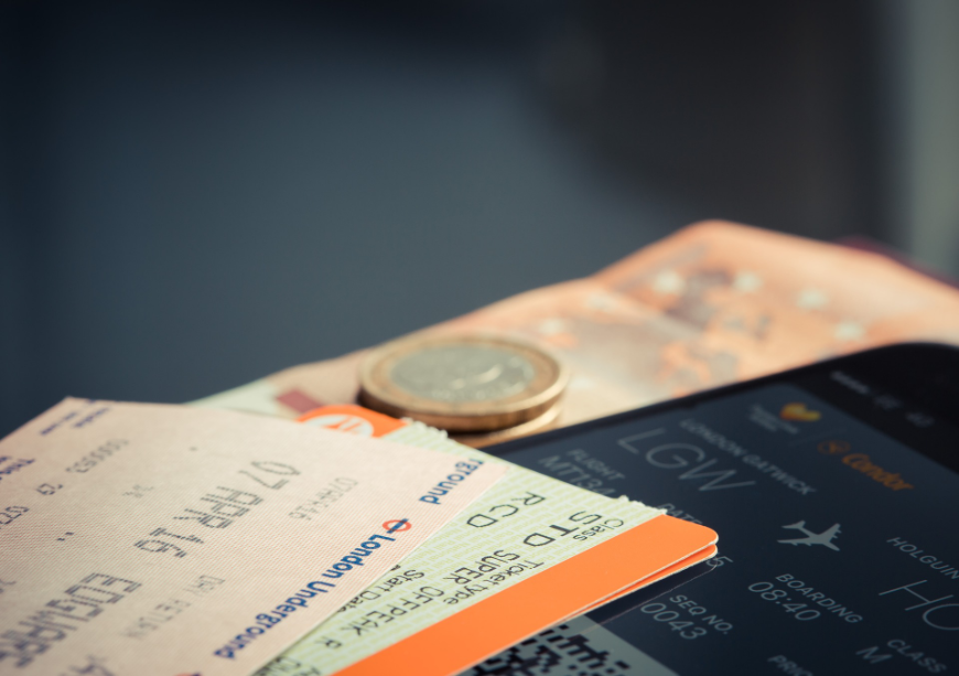 Tropical Holiday Image: Travel tickets laying on a table, with a coin currency or token on top of them.