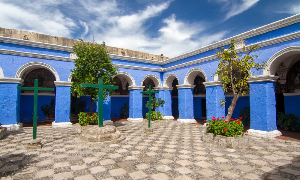 Unique Peru Image: The courtyard of a bright blue building is filled with tile, green crosses, and vibrant flowers.