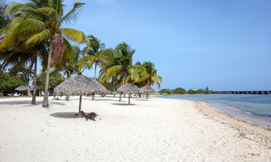 Vacation In Cuba Image: A beautiful but empty Cuban beach is dotted with straw umbrellas.