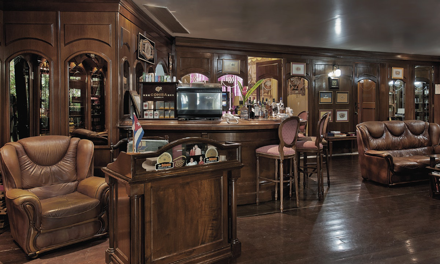 Vacation In Cuba Image: The rich and polished wooden interior of a cigar bar.