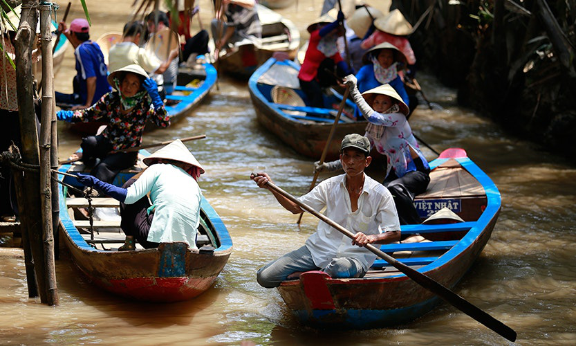 Vietnam Island Destinations Image: Locals paddle their boats in the water as they go about their daily lives.