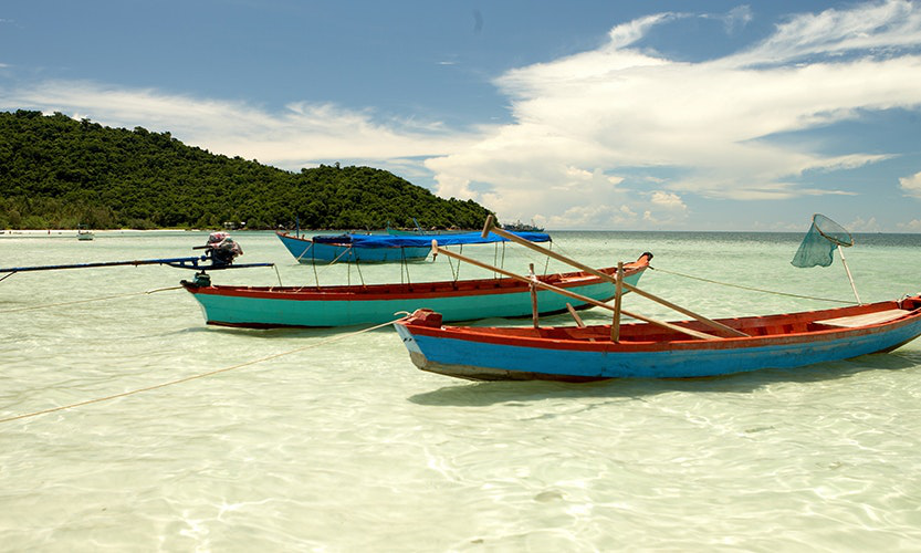 Vietnam Island Destination Image: Two long and colorful boats have been pulled up to the shore.
