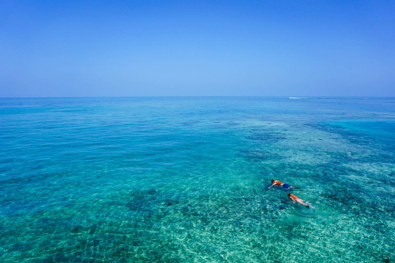 What To Pack Image: An aerial shot of two people snorkeling in crystal clear turquoise colored water.