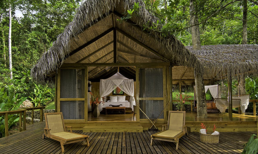 Why Is Costa Rica The Happiest Country Image: An ecolodge with a thatched roof has a bedroom which opens up to an outdoor space. 